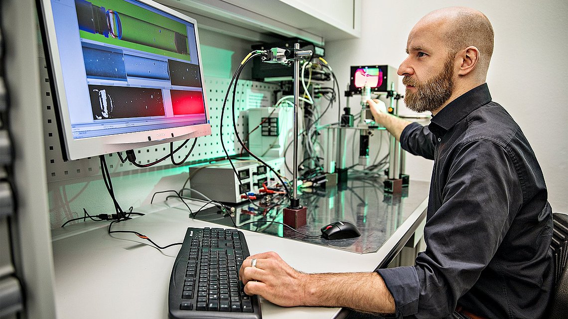 Foto eines Ingenieurs im Laboram Computer nehen einem Aufbau von Messinstrumemten